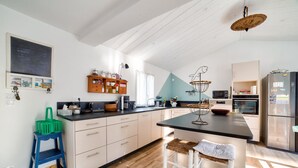 A modern kitchen with a central island, wooden cabinets, and a built-in oven. - Private access to the beach - House for 6 (Barbâtre)