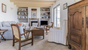 A living room with a sofa, chairs, a coffee table, a fireplace, and bookshelves. - Nice house and its veranda for a nice holiday (Saint-Philibert)