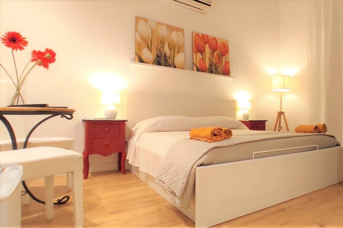 A bedroom with a bed, bedside tables, a desk, and a chair.
