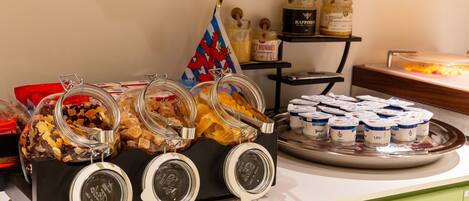 A buffet with various food items, including jars of pickles and containers of yogurt.