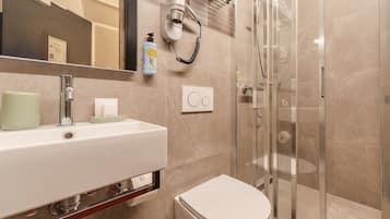 A modern bathroom with a sink, toilet, and glass shower enclosure.