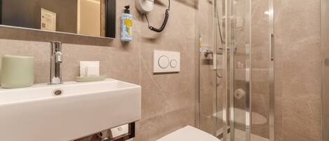 A modern bathroom with a sink, toilet, and glass shower enclosure.
