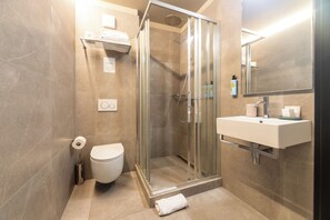 A modern bathroom with a glass-enclosed shower, a toilet, and a sink with a mirror above. - Kazakiwi (Luxembourg City)