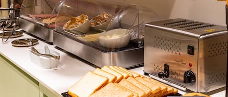 Montaje de bufé con diferentes alimentos, una tostadora y una cesta de pan.