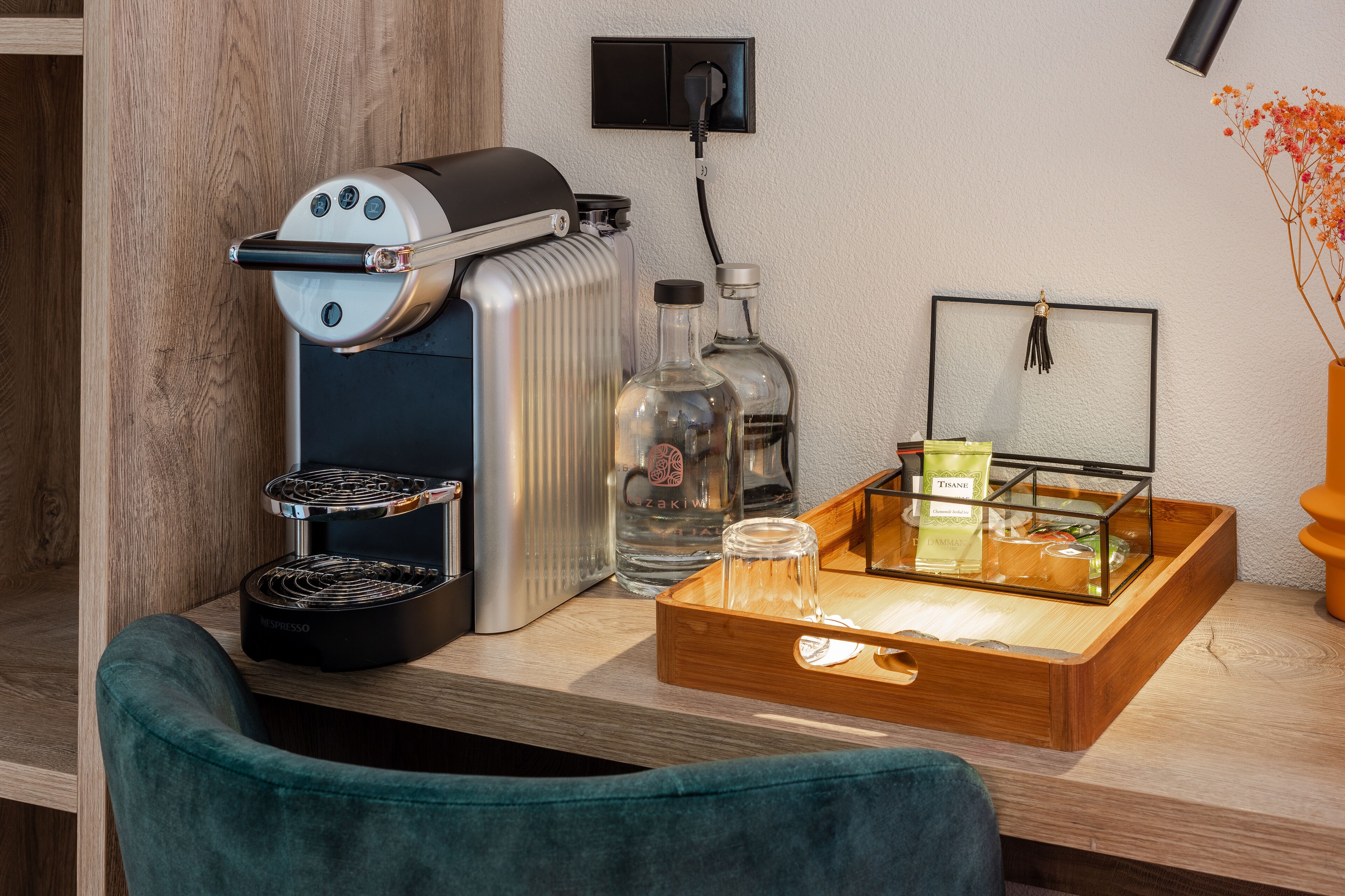 Una kitchenette con una cafetera, un hervidor y un recipiente de vidrio sobre una encimera de madera.