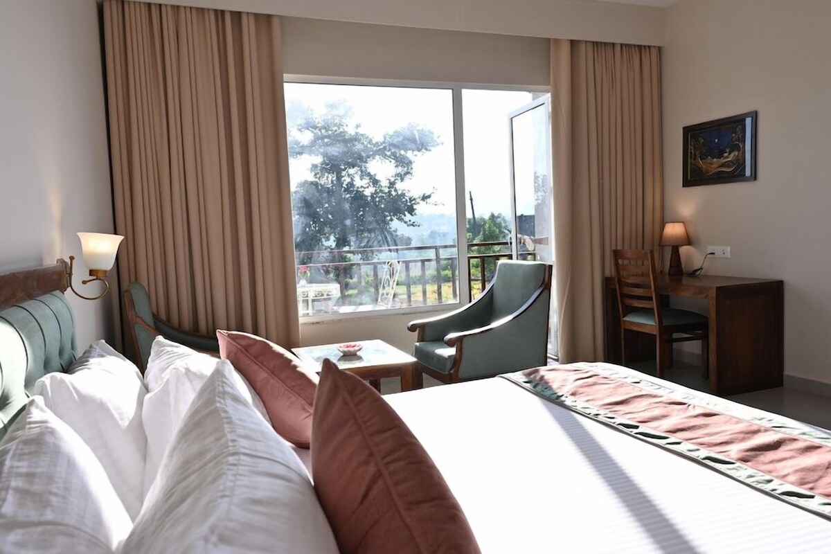 Una habitación de hotel con cama, escritorio, silla y vistas al exterior.