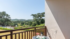 A balcony with a table and chairs, a view of greenery and hills, and a railing. - Kumbhal Exotica Resort Kumbhalgarh (Kumbhalgarh)