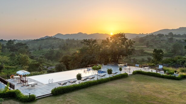 A pool area with lounge chairs, a barbecue setup, and a view of the surrounding landscape. - Kumbhal Exotica Resort Kumbhalgarh (Kumbhalgarh)