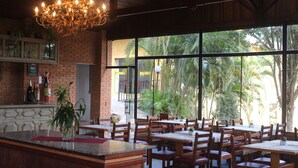 A restaurant with brick walls, large windows, wooden tables, and a chandelier. - PARADIES HOTEL EXPRESS (Jarinu)
