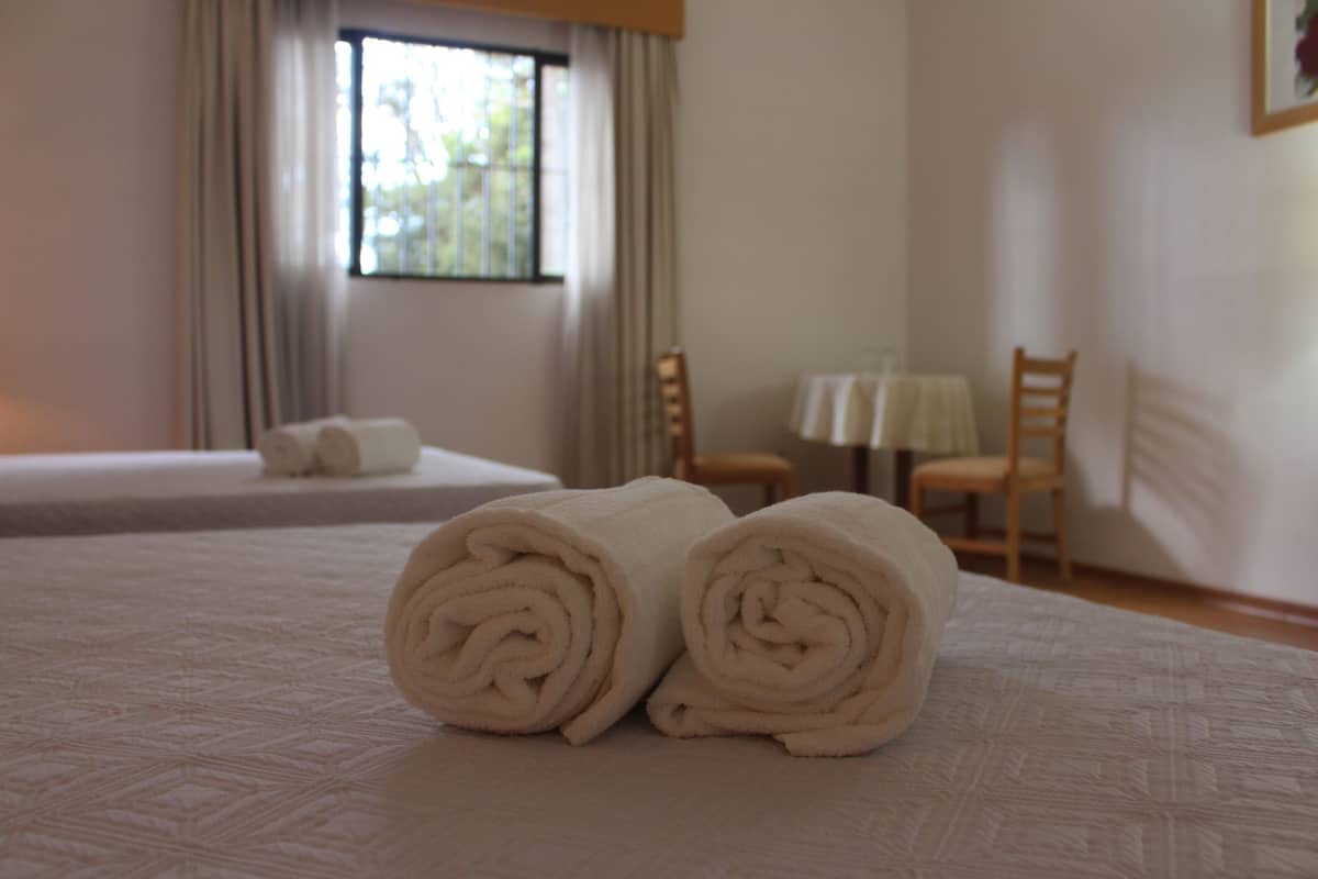 Una cama bien hecha con toallas blancas dobladas en un cuarto de hotel.