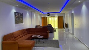 A modern living room with a sectional sofa, a coffee table, and a flat-screen TV. - SEA VIEW APARTMENT (DAKAR)