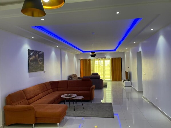 A modern living room with a sectional sofa, a coffee table, and a flat-screen TV.