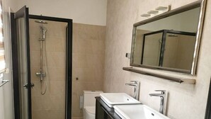 A modern bathroom with a glass-enclosed shower, a double sink vanity, and a large mirror. - SEA VIEW APARTMENT (DAKAR)