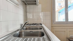 Een keuken met twee spoelbakken, een gasfornuis en een raam met uitzicht op gebouwen.
