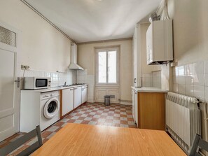 A kitchen with a washing machine, microwave, and a radiator.