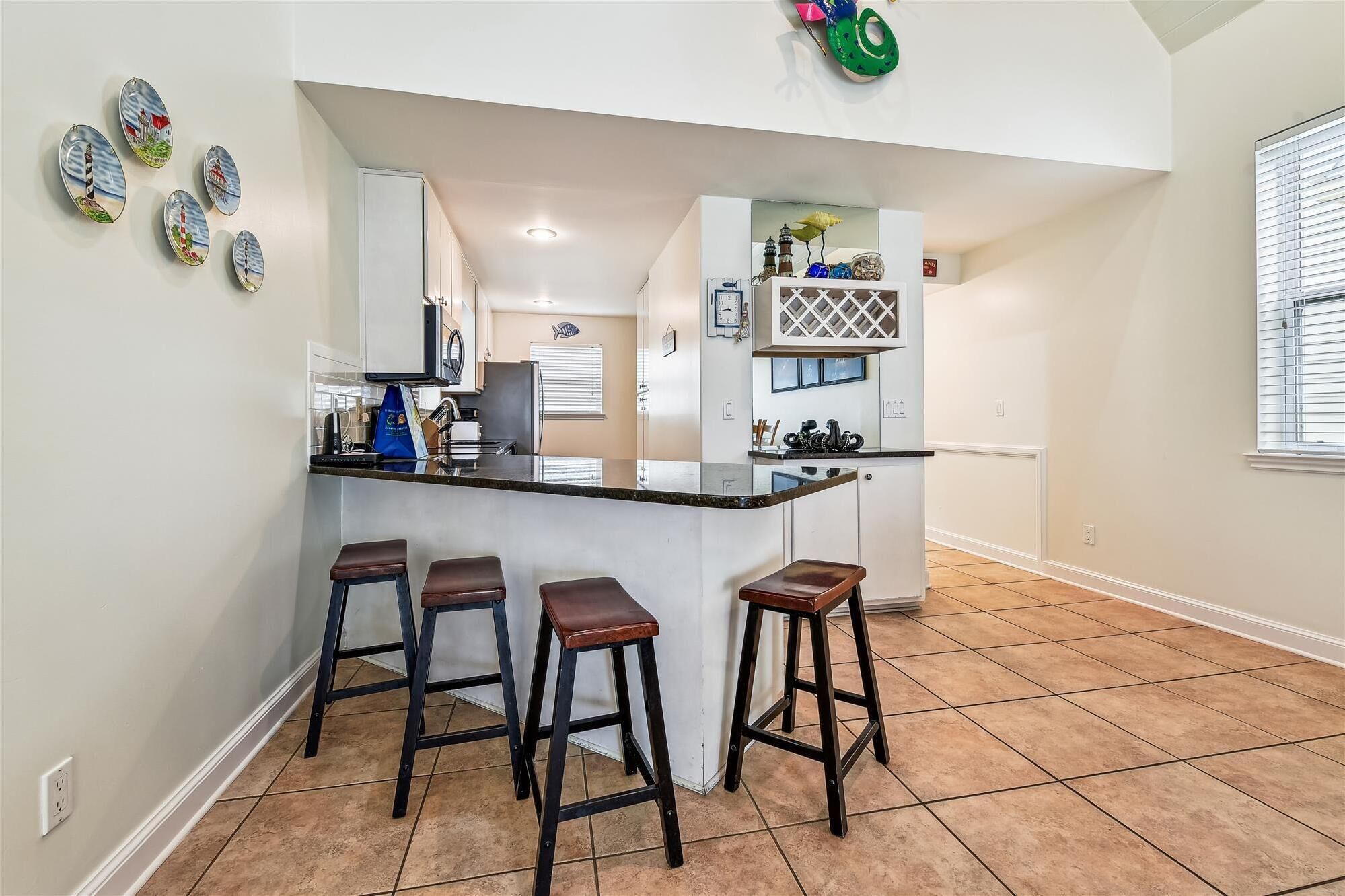 Una cocina con una isla central, tres taburetes y un tapiz decorativo.