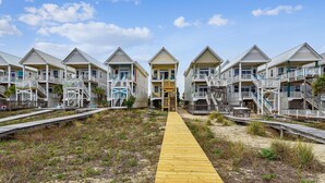 A row of beach houses with multiple balconies and a wooden walkway leading to the beach. - Welcome to The Sandbox! (St. George Island)