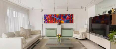 A modern living room with a sofa, armchairs, a coffee table, and a TV.