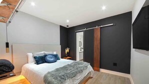 Une chambre à coucher moderne avec un lit, une table de chevet et un grand miroir.