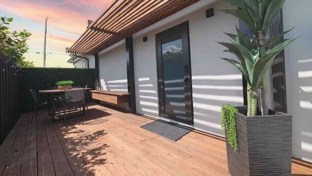 Une terrasse moderne avec une plateforme en bois, une table et des chaises, ainsi qu’une plante en pot.