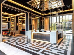 A modern lobby with a geometric patterned floor, a reception desk, and bookshelves. - Londwell - Stunning Designer Penthouse, US Embassy (London)