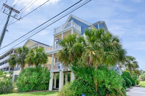 A multi-story building with balconies, surrounded by lush greenery and palm trees. - Large 6BR Home w/ Private Pool & Ocean Views (Surfside Beach)