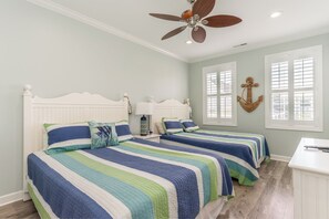 A bedroom with two beds, a ceiling fan, and a window with shutters. - Large 6BR Home w/ Private Pool & Ocean Views (Surfside Beach)