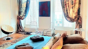 A bedroom with a bed, a chair, a small table, and curtains.