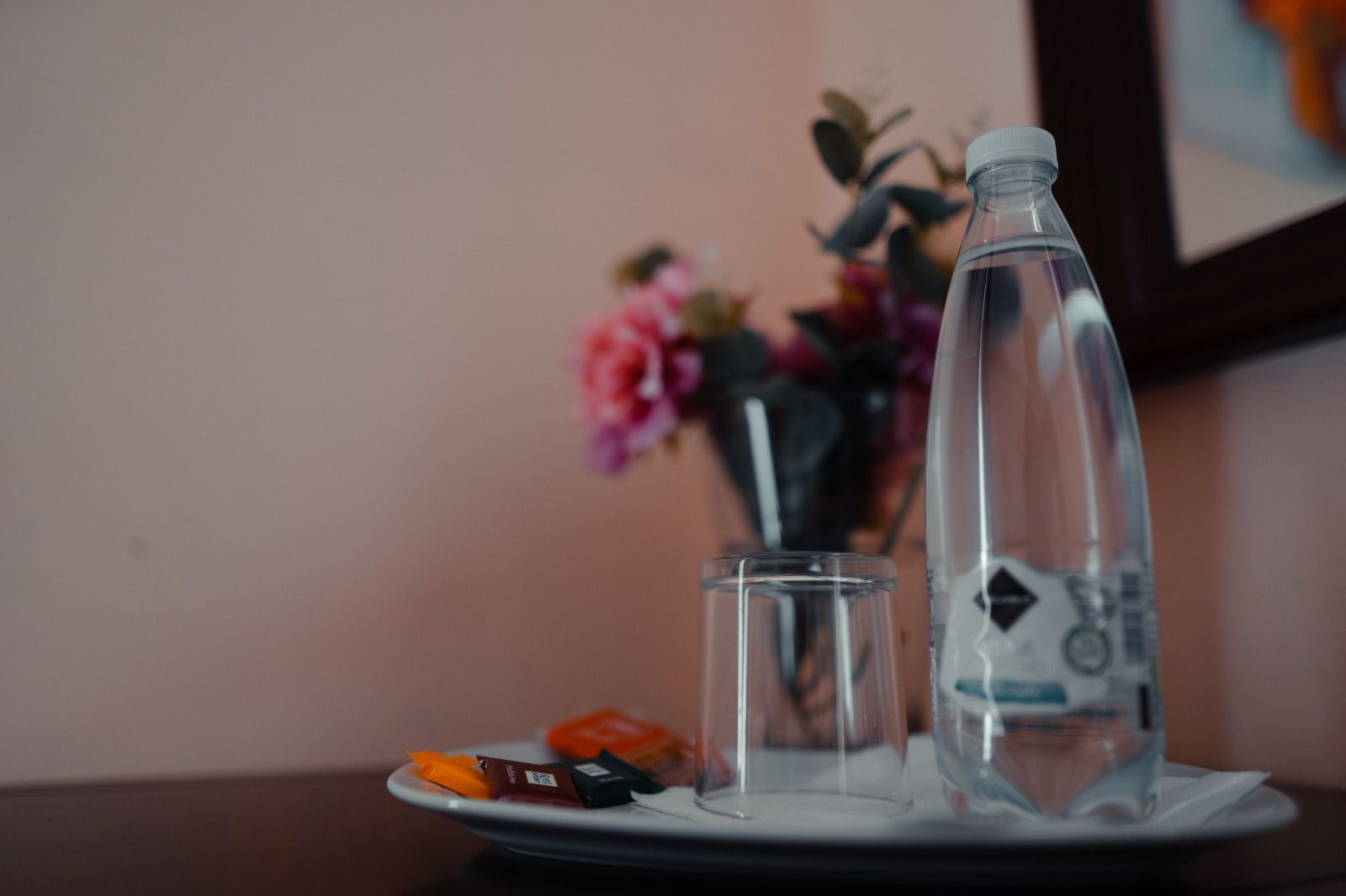 Una mesa con una botella, un vaso y algunos bocadillos.