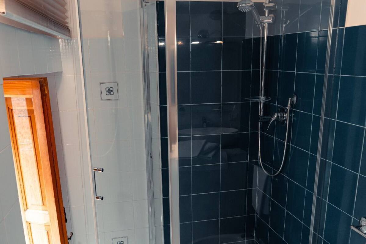 A modern bathroom with a glass-enclosed shower, white tiles, and a toilet.