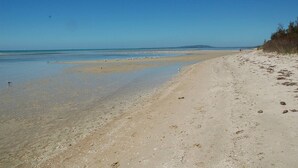 A sandy beach with clear water and a distant shoreline. - Capel Luxe (Capel Sound)