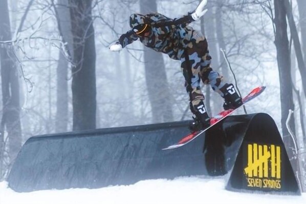 Un snowboarder realizando un truco sobre un riel.