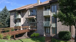 Un immeuble à plusieurs étages, doté d’une façade en briques, de balcons et d’un pont en bois menant à l’entrée.