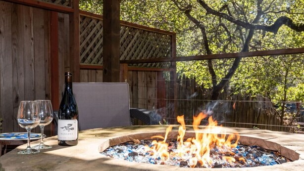 A fire pit with flames, a bottle of wine, and two glasses on a table outdoors. - Vineyard Cottage w/ Fire Pit | Chalk Hill Wine Country (Healdsburg)