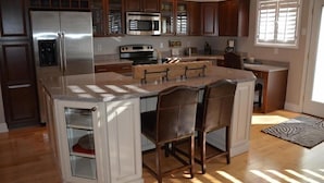 A modern kitchen with a central island, stainless steel appliances, and wooden cabinetry.