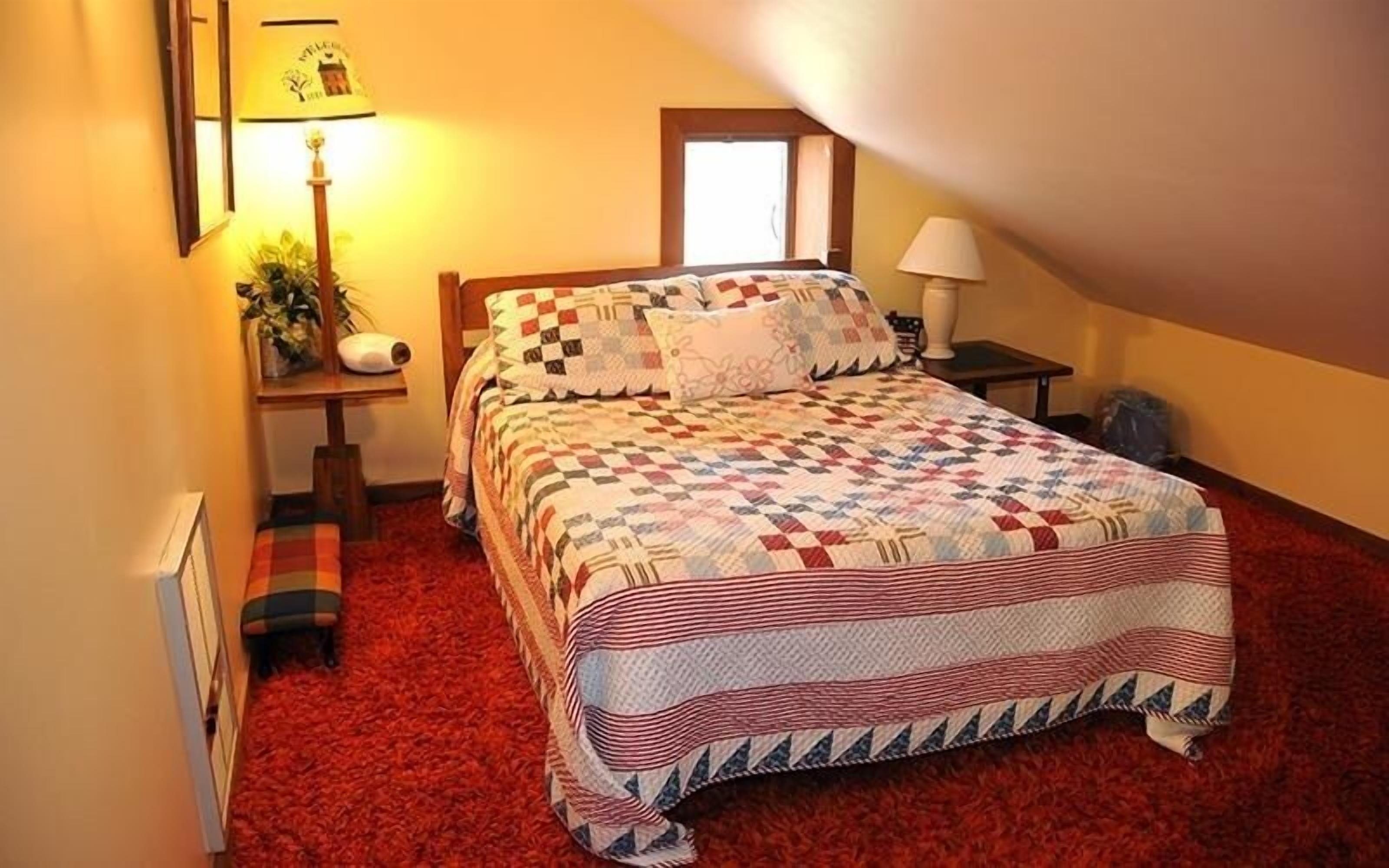 Un dormitorio con una cama grande, una mesita de noche, una lámpara y una ventana.