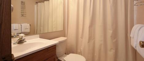 A bathroom with a sink, toilet, and shower curtain.