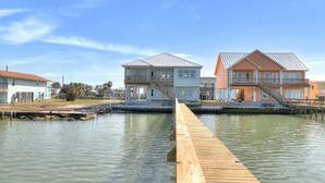 A waterfront property with a wooden dock leading to a house with a balcony and a second house with a staircase. - Soggy Pollards 5 Bedroom Home by RedAwning (Rockport)