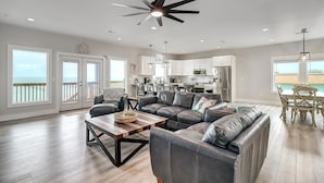 A spacious living room with a large sectional sofa, a wooden coffee table, and a ceiling fan. - Soggy Pollards 5 Bedroom Home by RedAwning (Rockport)