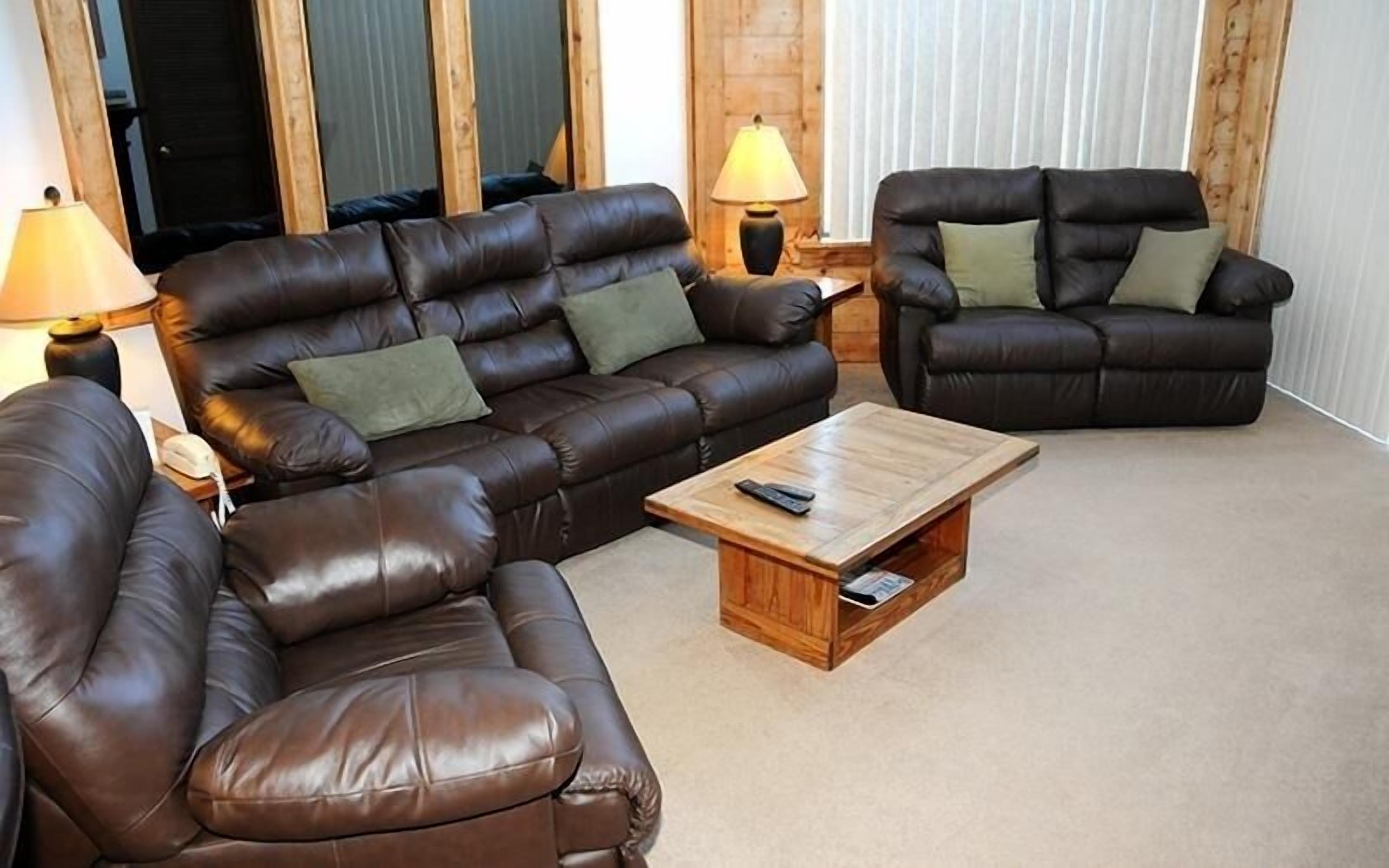 A living room with two leather sofas, a wooden coffee table, and two lamps.