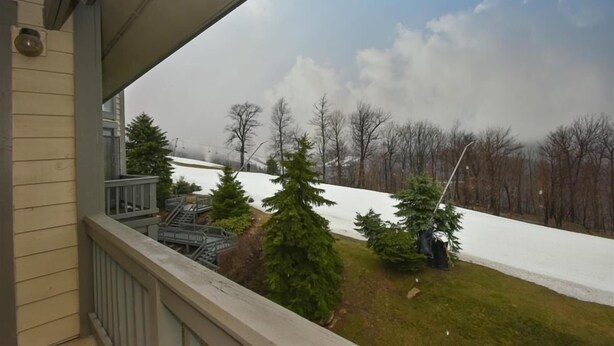 Ein Balkon mit Blick auf einen verschneiten Garten und kahle Bäume.