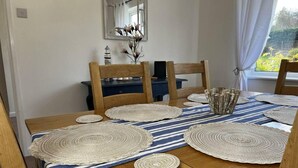 A dining table with woven placemats, wooden chairs, and a blue-striped table runner.