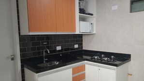 A kitchen with black countertops, white cabinets, and a gas stove. - PRAIA FLATS TEMPORADA BLUE 03 NO CENTRO DE PORTO DE GALINHAS (Ipojuca)