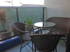 A balcony with wicker furniture, potted plants, and a tiled floor. - PRAIA FLATS TEMPORADA BLUE 03 NO CENTRO DE PORTO DE GALINHAS (Ipojuca)