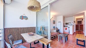Uma área de refeições com mesa e cadeiras, um lustre e vista para a cozinha.