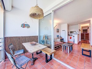 Un comedor con una mesa y sillas, una lámpara colgante y vista a la cocina.