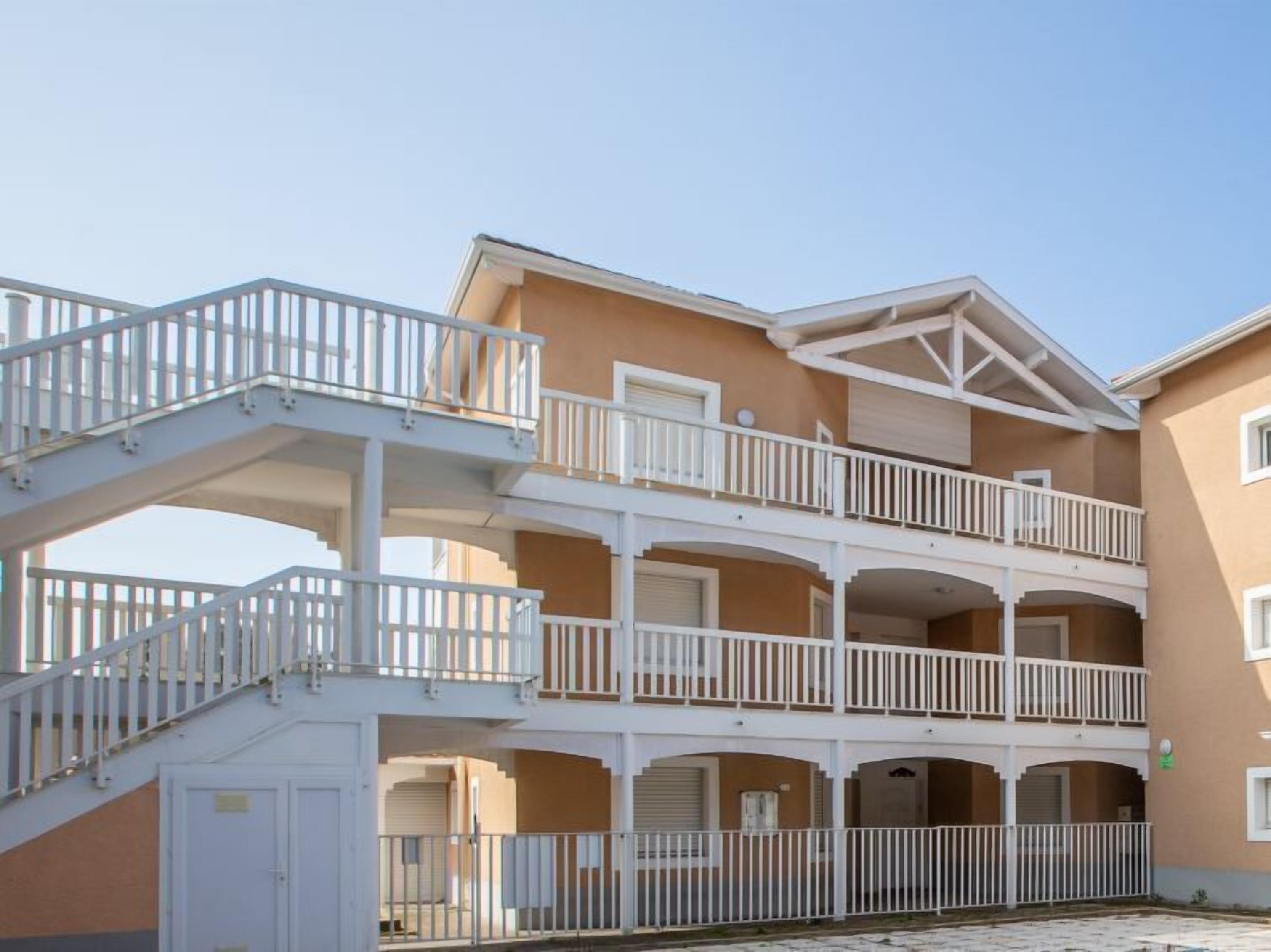 A multi-story building with balconies and a staircase.