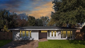 A modern single-story house with a covered patio, a driveway, and a well-maintained lawn.