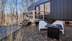 Uma cabana moderna com telhado de metal, um deck de madeira e uma área com lareira.