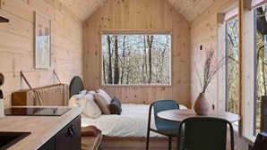 Quarto acolhedor de cabana com uma cama, uma escrivaninha e uma cadeira.